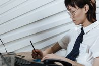 Man in White Shirt Writing on Paper