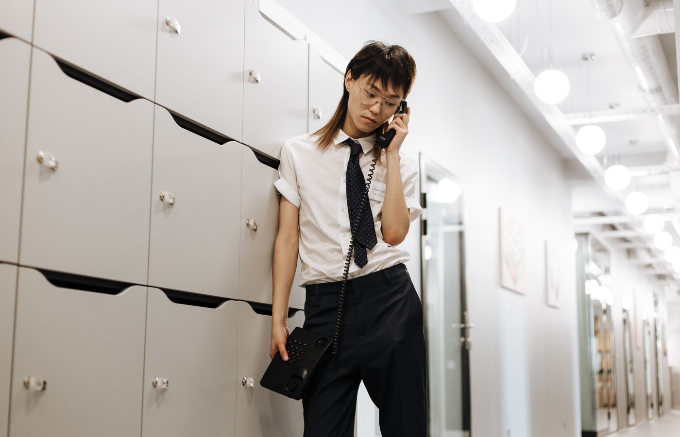 Asian man in office attire talking on phone in a contemporary office setting.