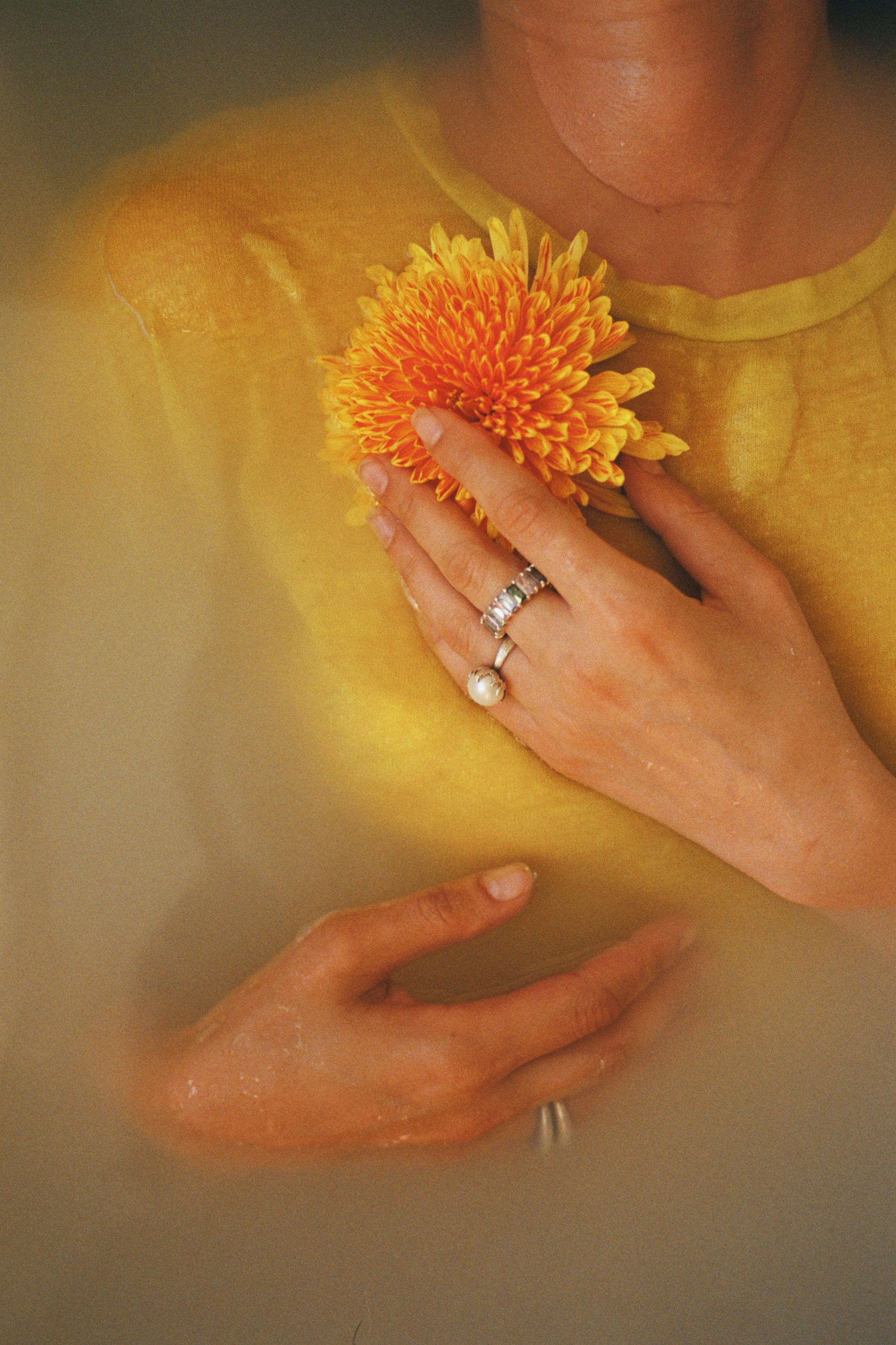 A serene portrait of a woman holding a yellow chrysanthemum in water, exuding elegance and tranquility.