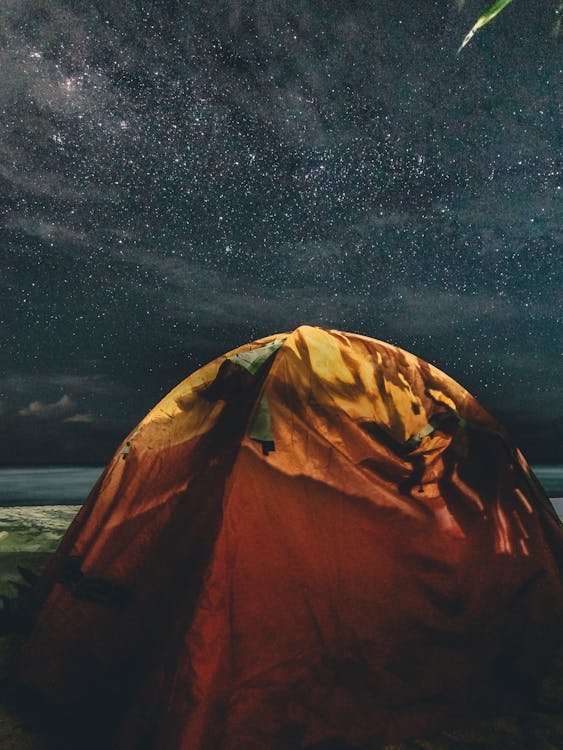 星空の下でオレンジと緑のキャンプテント