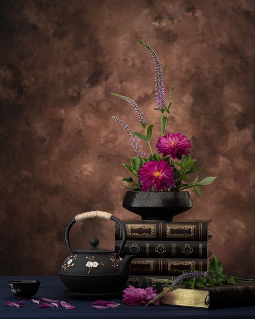 Free Intricate still life featuring flowers, antique books, and a vintage teapot on a textured background. Stock Photo