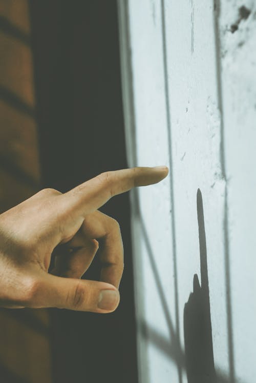 Close-Up Photo of a Person's Finger Touching a White Wall