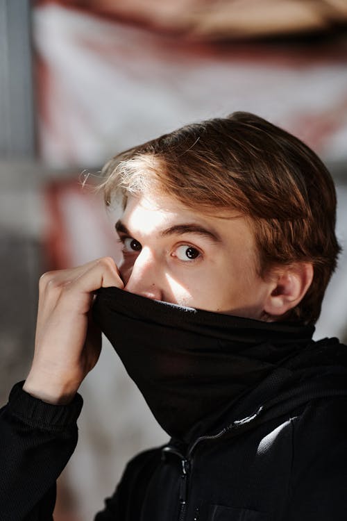 Close-Up Photo of a Man Covering His Mouth with a Black Cloth