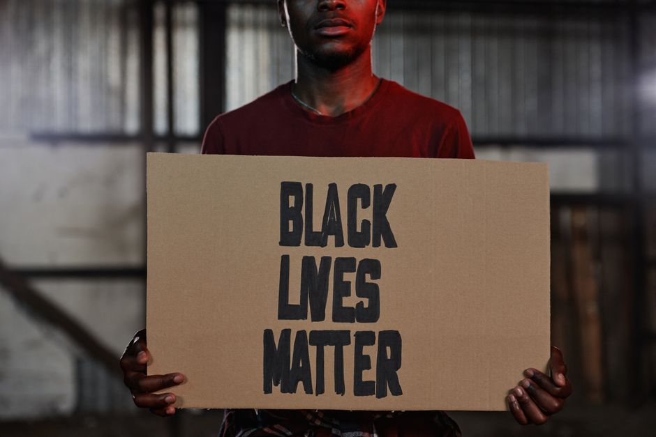 A person holding a Black Lives Matter sign during an indoor protest. Symbol of activism and social justice.
