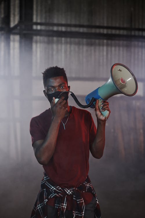 Free Man in Red Crew Neck T-shirt Wearing Face Mask while Holding Megaphone Stock Photo