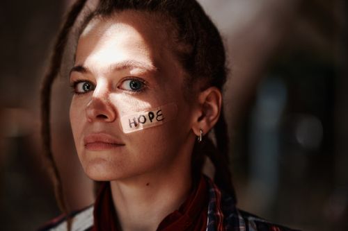 Free Close-up portrait of a woman with 'hope' written on a band aid. Depicts resilience and optimism. Stock Photo