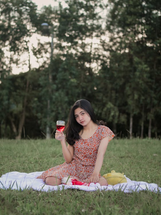 Photo of a Woman in a Floral Dress Holding a Glass of Wine