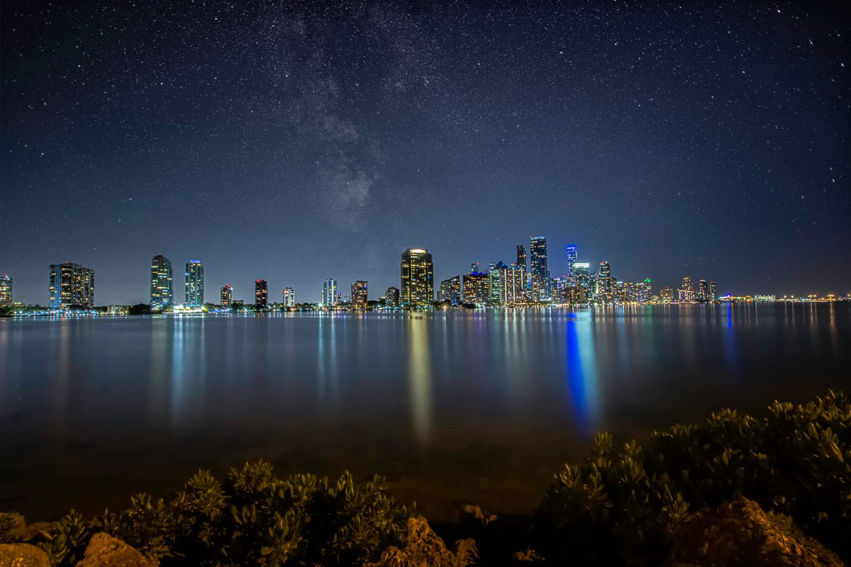 Miami skyline at night with lights reflected on water
