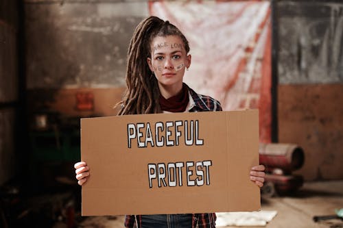 Free A Woman Holding a Cardboard with Words Written on Her Face Stock Photo