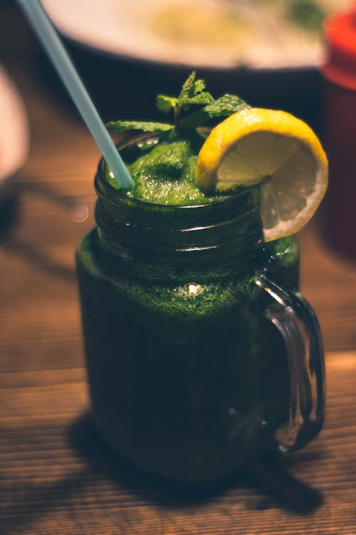 Photographie En Gros Plan D'une Tasse En Verre Transparent Mason Jar Avec Jus Vert Et Garnitures D'agrumes En Tranches