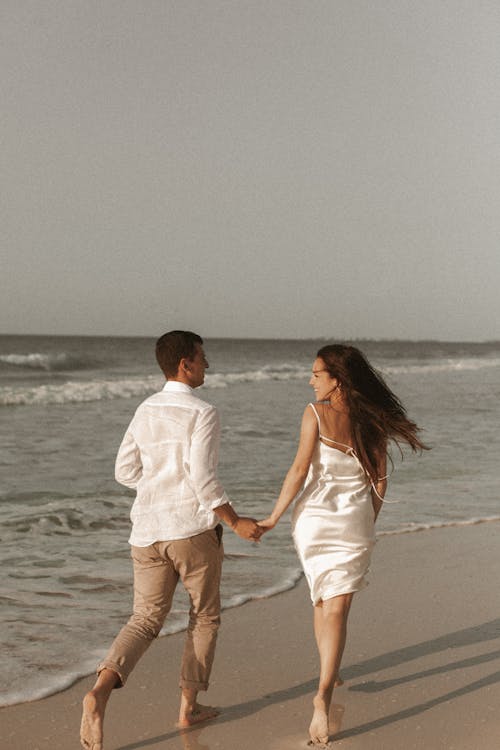 Couple Holding Hands While Walking On The Beach