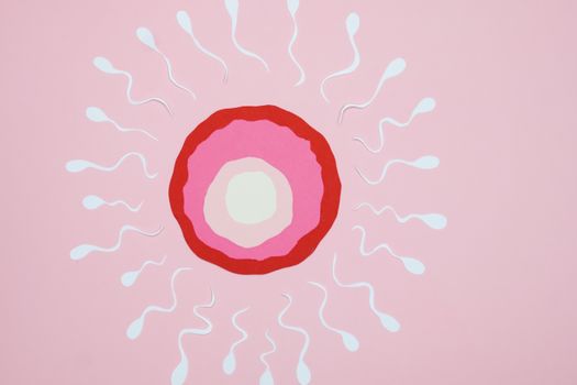 Conceptual art of fertilization with sperm and egg on a pink background.