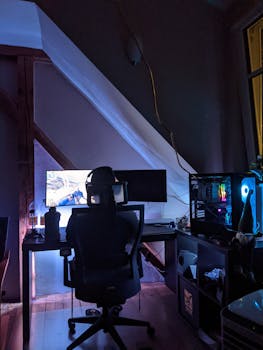 A dimly lit home office featuring a gaming setup with PC and monitor.