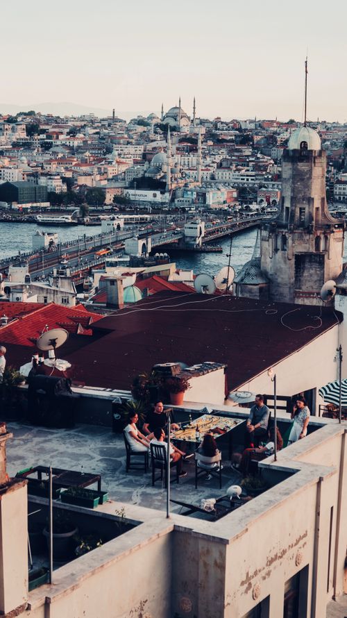 Free A vibrant rooftop gathering with a stunning view of Istanbul's historic skyline, featuring the Golden Horn and Galata Bridge. Stock Photo