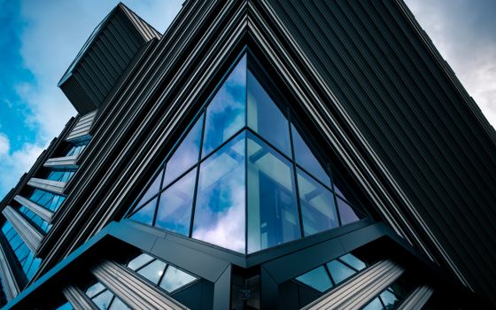 Striking modern building facade with angular glass features against a blue sky.