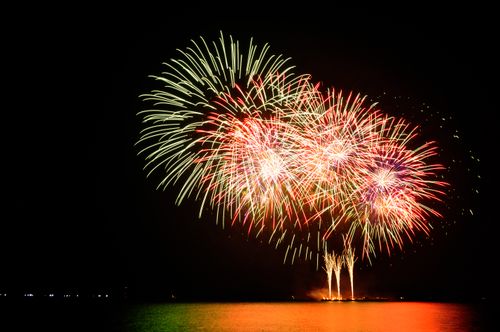 Free Vibrant fireworks lighting up the night sky and reflecting on the water in a stunning display. Stock Photo