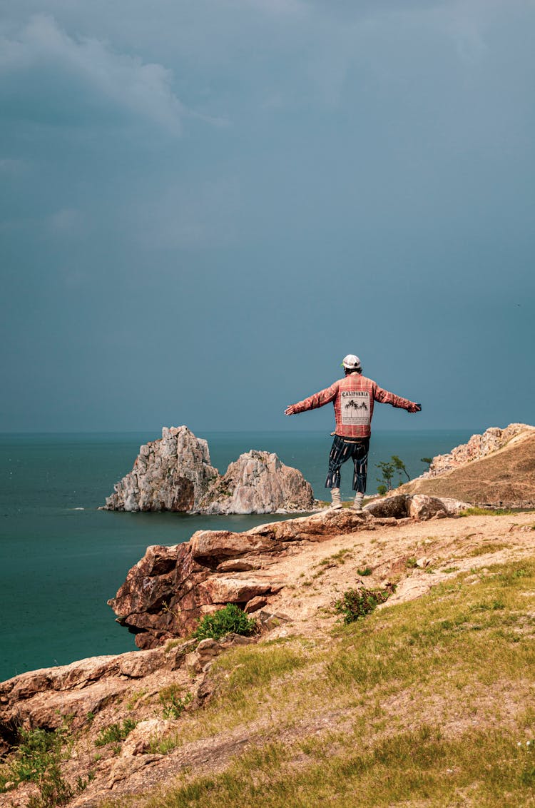 Man Standing On Sea Shore With Arms Stretched