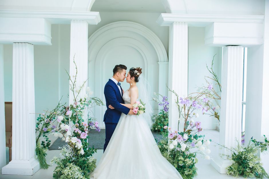 Newlywed couple surrounded by pale flowers