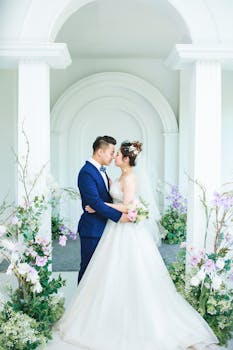 A stylish Asian groom and bride share a loving embrace at their indoor wedding ceremony.