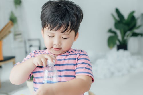 Close Up Photo of a Boy Holding a Plastic Bottle