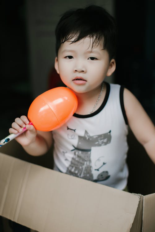 A Little Boy in a Tank Top Holding a Toy