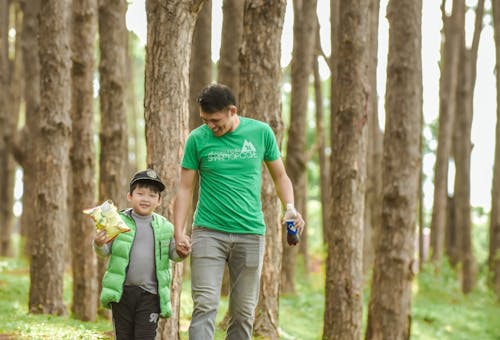 Free Man in Green Shirt Holding the Hand of a Boy Stock Photo