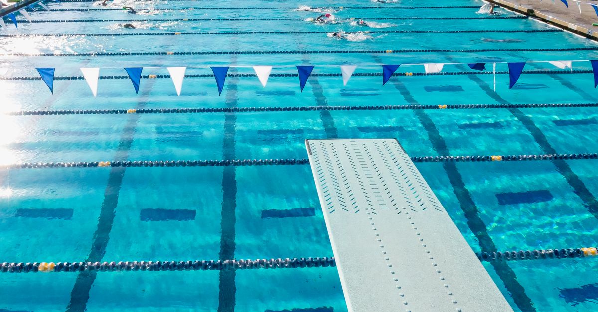 Aerial perspective of an Olympic-size swimming pool showing lanes and diving board in sunny California.