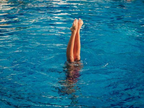 Free Athlete executes a perfect upside-down pose in a swimming pool. Stock Photo