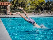 Person in Floral Shorts Jumping in Swimming Pool