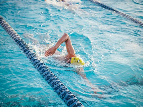 Swimmer in yellow cap performing front crawl in swimming pool during daytime.