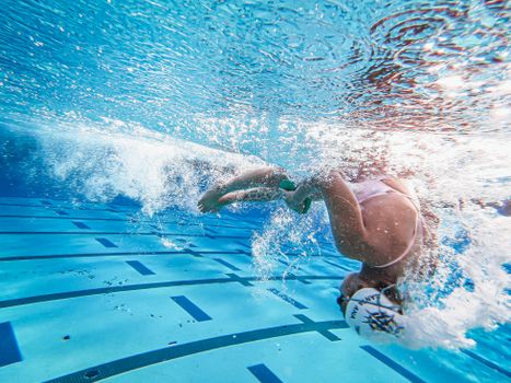 Underwater photo of a woman swimmer performing a flip turn in a swimming pool.