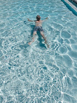 Boy enjoying a relaxing swim in a crystal-clear outdoor pool.