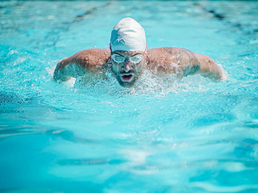 focused swimmer performs a stroke in a vibrant turquoise pool, showcasing athletic prowess and dedication.