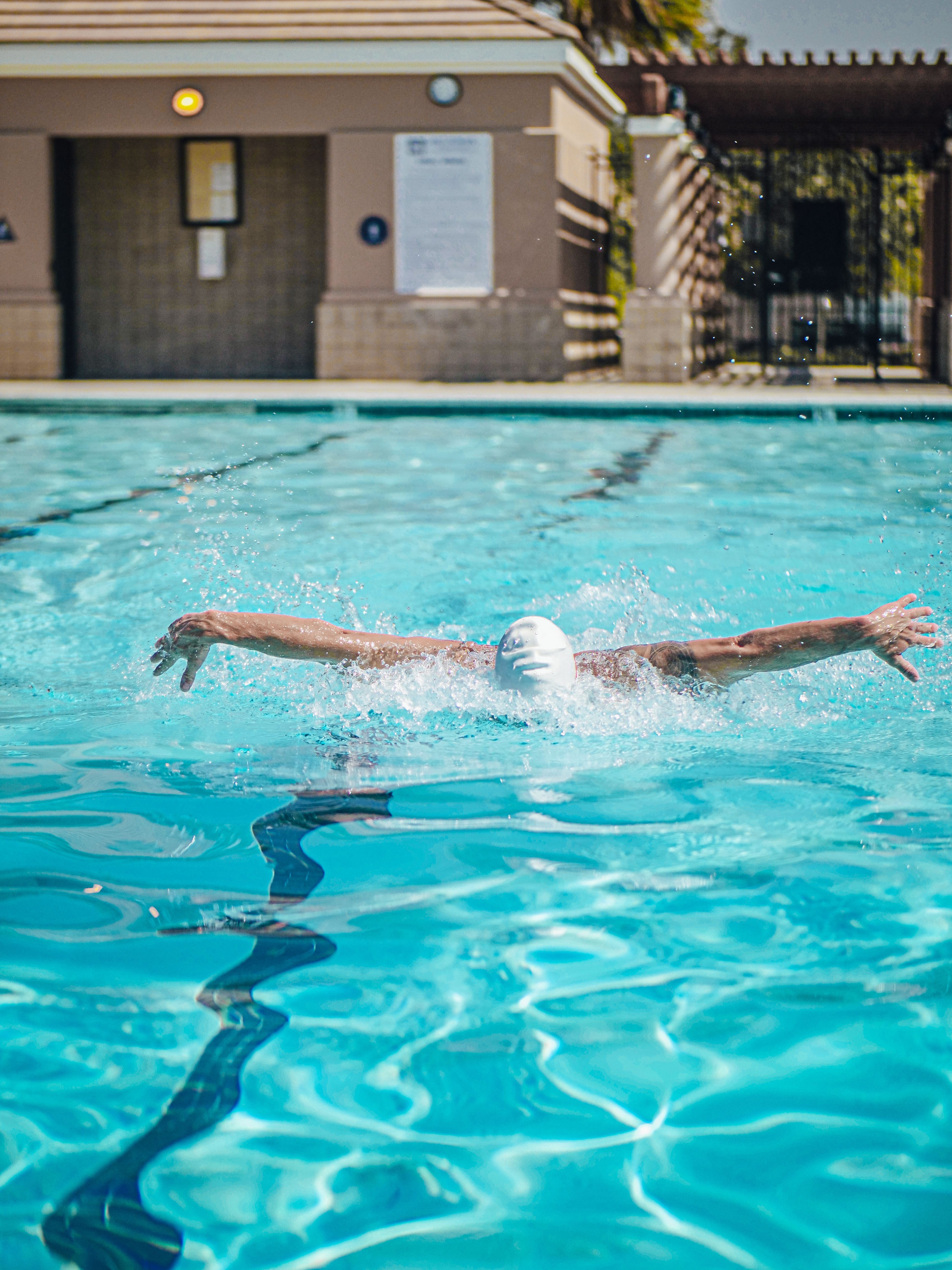 A swimmer performing a butterfly stroke in an outdoor pool, showcasing athletic training.