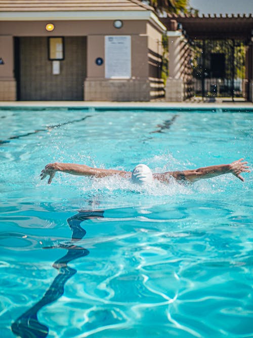 A Person with a White Swimming Cap Doing the Butterfly Stroke