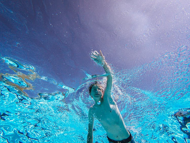 Shirtless Man Swimming In A Pool