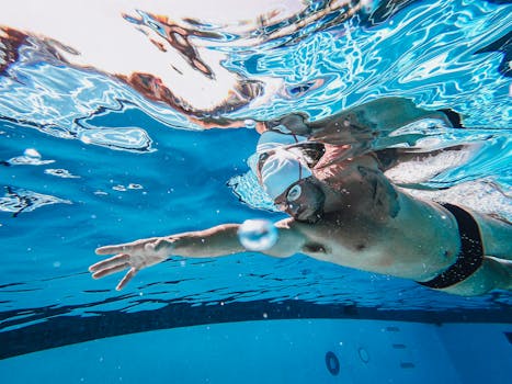 Swimmer practicing strokes underwater in a clear swimming pool, showcasing athletic technique.