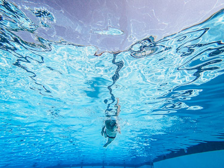 Kid Wearing Swim Trunks Swimming On A Pool