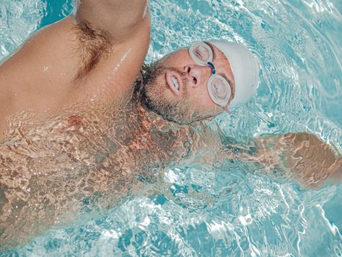 Free Focused athlete performing a backstroke in a clear swimming pool. Stock Photo