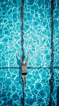 Dynamic aerial view of a swimmer in a brightly lit pool showcasing athletic prowess.