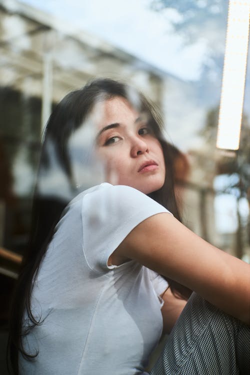 Woman Sitting Beside a Glass Window