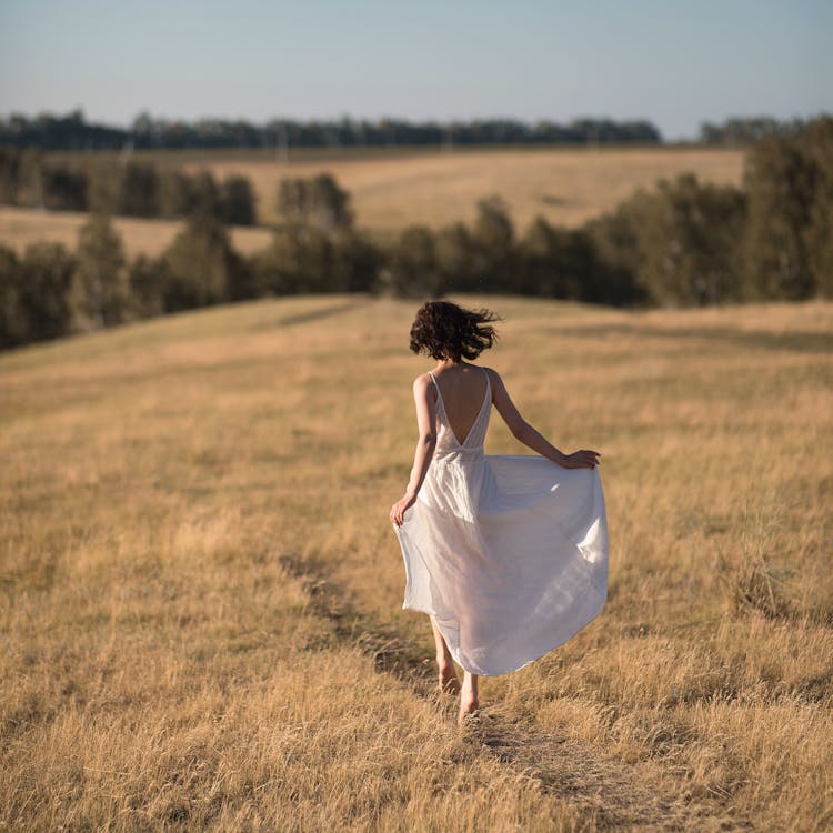 Woman In Dress Running On Meadow