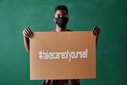 A Man Wearing a Face Mask Holding a Poster