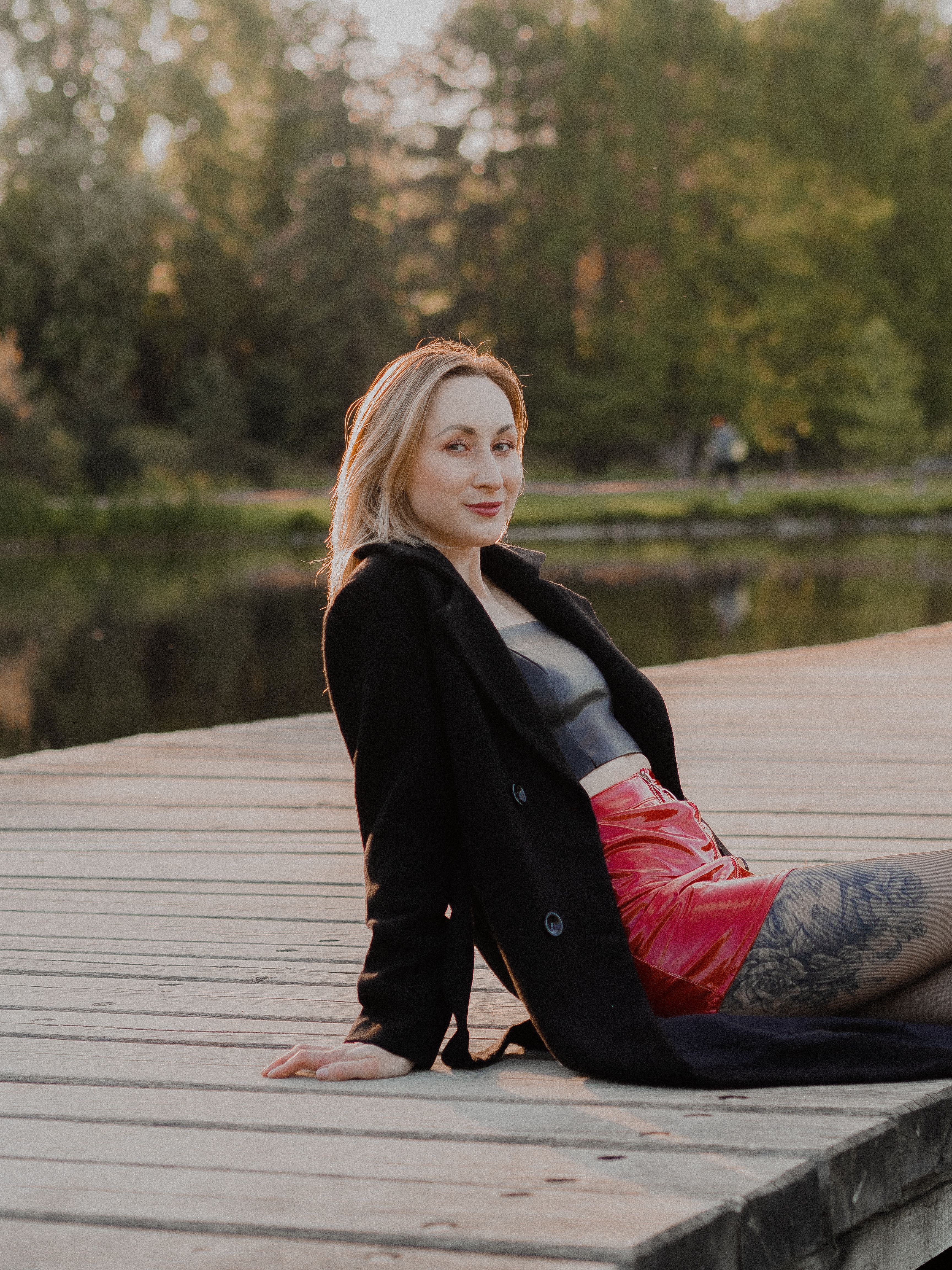 A Woman in Black Coat Sitting on a Wooden Dock · Free Stock Photo
