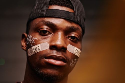 Free Close-up portrait of a man with band aids displaying 'peace' and 'care' messages. Stock Photo