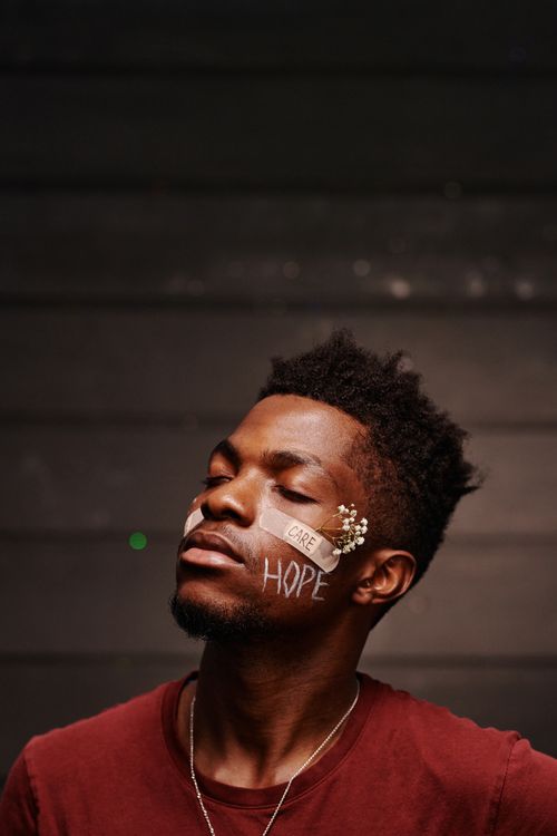 Free Close-up conceptual portrait of a man with face art, band aid, and hopeful message. Stock Photo