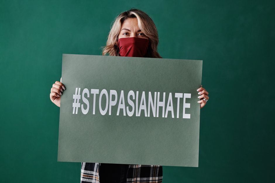 여성이 #StopAsianHate가 적힌 팻말을 들고 인종차별 반대 캠페인에 참여하고 있습니다.
