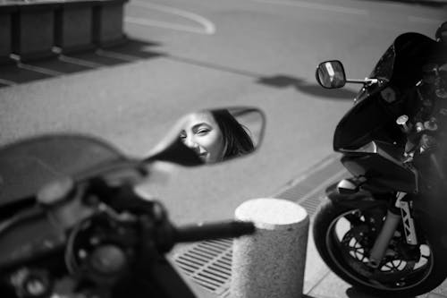 Free Grayscale Photo of a Woman's Reflection in a Side Mirror on a Motorcycle Stock Photo