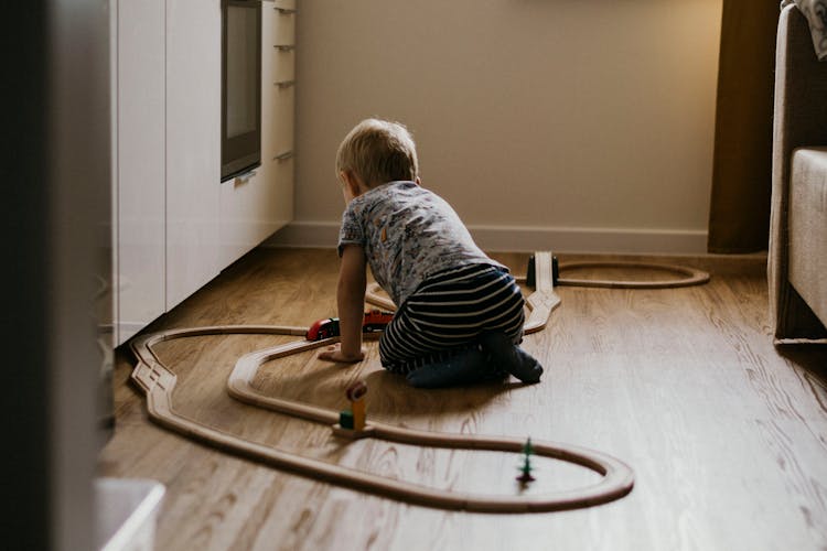 Boy Playing With Toy Railway On Floor