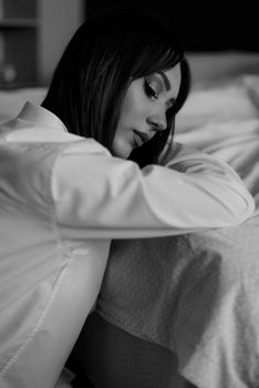 Elegant black and white portrait of a woman resting her head on a bed with eyes closed.